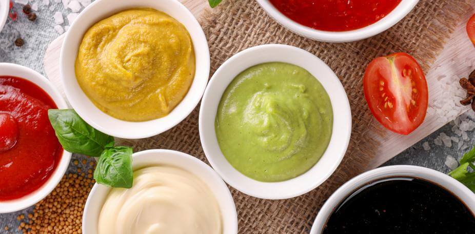 An assortment of colorful Mediterranean sauces in small white bowls,